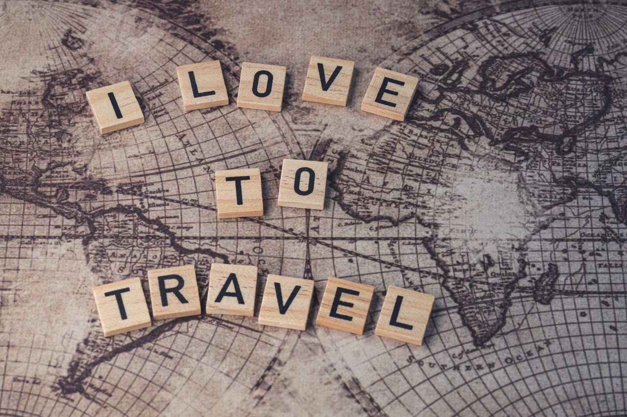 Wood scrabble tiles spelling 'I Love to Travel' on a vintage map.